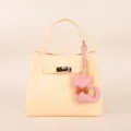 Stylish light yellow leather handbag with cute cat charm and metal lock closure. - BHT07 Pink Kitten