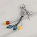 Vista detallada de llavero trenzado colorido con lazo de metal, colgante y cuentas. - Colgante 14