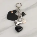 Close-up detail of chic black and silver heart keyring charm with leather and metal pendants. - Bag Charm 18