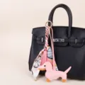 Λεπτομέρεια μπρελόκ τσάντας dachshund από ροζ δέρμα, με πλεγμένο φουλάρι twilly και φούντα. - Ροζ μεταξωτό μαντίλι με φούντες + ροζ σκυλάκι ντάξχουντ