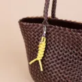 Minimalist leather braided rope bag charm and creative car keychain pendant detail shot. - Yellow
