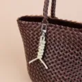 Dark brown woven leather tote bag with stylish light green knot keychain pendant accessory. - Light Green