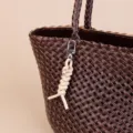 Dark brown woven leather tote bag with a chic cream knotted rope keychain and metal clasp. - Off White
