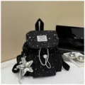 Detailansicht des schwarzen Mini-Rucksacks mit weißem Sternenmuster und silbernem Anhänger. - Mit Anhänger / Schwarz