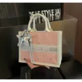 Detail view of the pink polka dot canvas tote bag featuring a silver star pendant and top handles. - With Charm / Pink