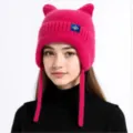Nahaufnahme der rosa gestrickten Katzenohrenmütze mit Ohrenklappen und Schneeflockenetikett. - Fuchsia