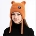 Detailansicht der orangefarbenen gestrickten Ohrenklappenmütze mit niedlichen Ohren für Winter. - Gelb