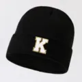 Black knitted beanie hat with a white and gold glitter letter K patch for versatile wear. - Adjustable / Letter K / Black