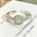 Primer plano detallado de un elegante anillo abierto de plata con circón verde claro y pavé. - Abierto Ajustable / Estilo De Circonia Verde Claro Cuadrada (JZ2214A)