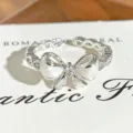 Close-up of exquisite silver bow ring with white enamel and sparkling zircon details. - White Enamel Bowknot Style (JZ1512A) / Adjustable Open