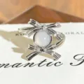 Close-up detail shot of the silver bow ring featuring sparkling zircon and milky center stone. - Double Bowknot Gemstone Style (JZ3680A) / Adjustable Open