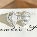 Detailed shot of a silver bow open ring sparkling with blue cubic zirconia stones. - Blue Zircon Bowknot Style (JZ4532A) / Adjustable Open