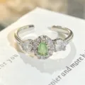 Primer plano detallado de anillo abierto de plata con circonita verde clara y piedras. - Abierto Ajustable / Estilo De Circonia Verde Claro Ovalada (JZ2415B)