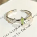 Primer plano detallado de un elegante anillo abierto de plata con circonitas verdes y blancas. - Abierto Ajustable / Estilo De Circonia Doble Verde Y Blanca Marquise (JZ5399A)