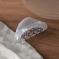 Gros plan détaillé d'une pince à cheveux triangulaire irisée translucide avec effet nacré. - 9cm / Violet de rêve