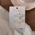 Primo piano di mollette per capelli floreali e a quadri dolci con fiocchi su carta. - Ovale A Quadri Rosa Con Fiori Rosa
