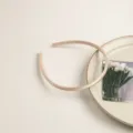 Vue detaillee d'un serre-tete fin en satin de couleur champagne, accessoire elegant chic. - Champagne