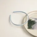 Gros plan du serre-tête fin en satin bleu clair, accessoire élégant pour coiffure. - Bleu clair
