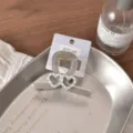 Close-up detail shot of sparkly rhinestone double heart hair claw clip on brand display card. - Gray Crossed Double Heart Hair Claw