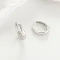 Close-up view of minimalist silver hoop earrings with a sleek polished metal design. - Oval / Silver