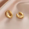 Close-up detail of stylish minimalist gold hoop earrings, perfect for everyday chic fashion. - Thick Hoop Style / Gold