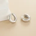 Detailed view of a pair of minimalist thick silver hoop earrings with a sleek polished finish. - Thick Hoop Style / Silver