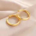 Close-up of simple polished gold hoop earrings resting on smooth satin fabric background. - Thin Band Style / Gold