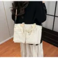 Detailed view of large capacity corduroy shoulder bag with multiple zipper pockets and top handles. - White