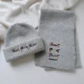Detailed view of grey knitted scarf and beanie hat set with cute dachshund embroidery. - Set / Gray