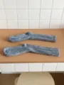 Graue dicke Wollsocken Strick Detail, weisse Fliesen Wand Hintergrund, warme Wintersocken - Grau