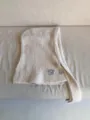 Detailed view of beige knit balaclava hood scarf, showing fine texture, buttons and brand tag. - Off White