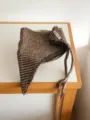Gros plan d'un foulard triangulaire en tricot marron avec liens, montrant texture et étiquette. - Brun Foncé