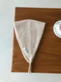 Nahaufnahme eines kuscheligen beigen Strick-Ohrwärmers aus Wolle auf einem Holztisch. - Elfenbein