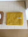 Primer plano detallado de una cálida bufanda de punto amarillo con etiqueta tejida. - Amarillo
