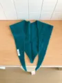 Detail view of a cozy wool triangular scarf featuring knitted textured patterns and tag. - Lake Blue