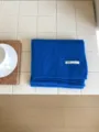 Primer plano detallado de una cómoda bufanda de punto azul doblada sobre azulejos blancos. - Azul zafiro