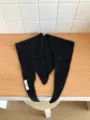 Detailed view of a black knit wool triangular scarf, featuring delicate floral knit texture. - Black