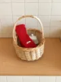 Detalle de bufanda tejida roja en cesta de mimbre mostrando textura acanalada y etiqueta. - Rojo