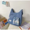 Vue détaillée du sac porté épaule décontracté avec poche avant à cordon à carreaux et étiquette. - Sans pendentif / Bleu foncé