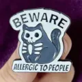 Detail shot of gothic skeleton cat enamel pin, featuring quirky text and smooth finish. - Skeleton Cat (Beware)