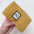 Detailed closeup of the yellow knitted hair band showcasing textured fabric and embroidered patch. - Turmeric