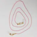 Detailaufnahme der rosa Perlenkette mit goldenen Verschlüssen für Brillen und Masken. - Rosa