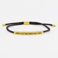 Dettaglio di bracciale in corda intrecciata a mano con barra in acciaio al titanio. - Tubo Oro - Corda Caffè (Con Cartolina)