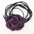 Vista dettagliata della rosa in tessuto viola scuro con cordoncini in pelle scamosciata nera. - Viola