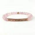 Vista dettagliata del braccialetto di perle in pietra rosa 6mm con citazione incisa. - Quarzo rosa e tubo curvo in oro rosa