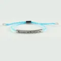 Primo piano del braccialetto regolabile intrecciato azzurro con barra metallica incisa. - Argento e Blu Lago