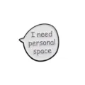 Close-up of a funny metal speech bubble brooch pin with personal space text design. - I Need Personal Space Style