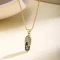 Close-up detail of gold evil eye slipper pendant necklace with sparkling zirconia stones. - Dark Blue