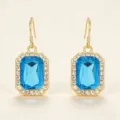 Vista dettagliata degli orecchini pendenti in cristallo blu con strass lucidi eleganti. - Dorato + Blu Acquamarina