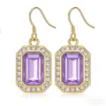 Primo piano dettaglio orecchini pendenti cristallo viola rettangolare bordo strass oro. - Dorato e viola